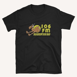 May include: Black t-shirt featuring a yellow and brown cartoon camel wearing headphones and the text "106 FM Rockin' the Bay".
