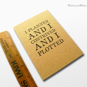 Könnte beinhalten: Ein braunes Notizbuch mit dem Text "I planned and I contrived and I plotted" in Schwarz gedruckt.