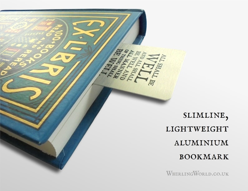 May include: A silver bookmark with the text "All shall be well and all shall be well and all manner of thing shall be well" is tucked into the corner of a blue book with gold lettering that reads "Ex Libris". The bookmark is described as "Slimline, Lightweight Aluminium Bookmark" and the website "WhirlingWorld.co.uk" is printed below.