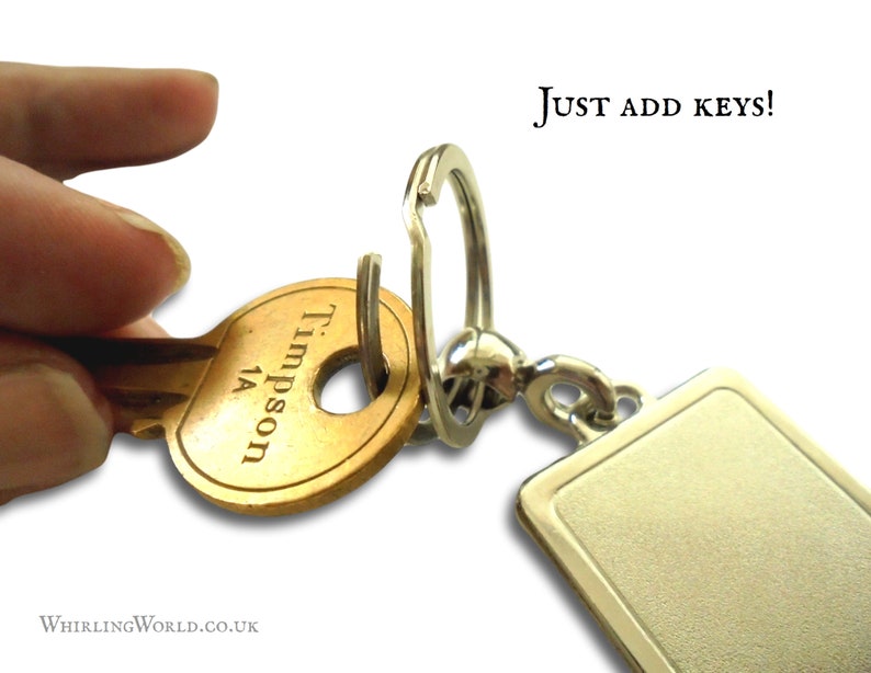 May include: A silver key chain with a blank rectangular tag and a silver split ring. A brass key with the inscription "Trimpson 1A" is attached to the ring. The text "JUST ADD KEYS!" is visible in the upper right corner of the image.