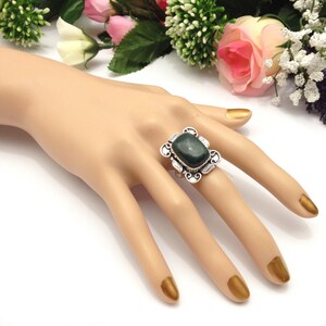 May include: A silver ring with a dark green gemstone set in a decorative filigree design.