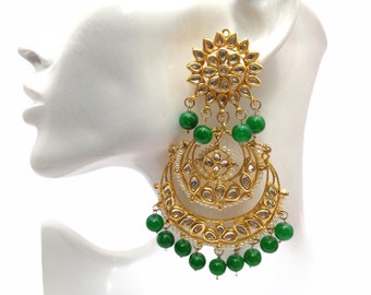 May include: Gold and green dangle earrings with a circular design and pearl accents. The earrings are long and feature multiple layers of beads.