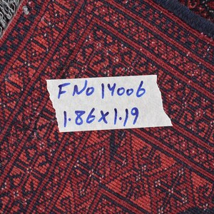 May include: Close-up of a red and black patterned rug with a white label that reads "F No 14006 1.86 x 1.19".