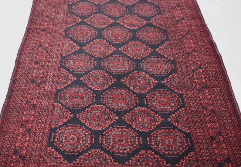May include: A traditional Persian rug with a dark blue background and intricate red and white floral patterns. The rug has a border with a repeating geometric design.