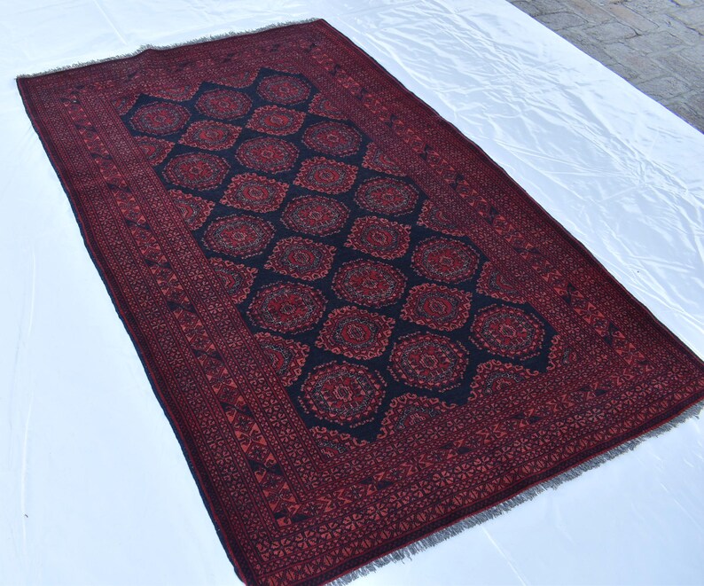 May include: A red and blue patterned rug with a geometric design. The rug has a fringed border.