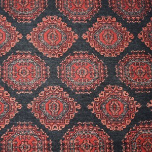 May include: A close-up of a traditional Persian rug with a dark blue background and intricate red and white patterns. The rug features a repeating design of floral motifs and geometric shapes.