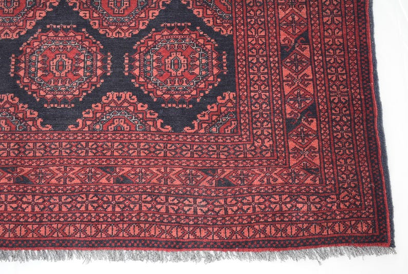 May include: A red and black patterned rug with a geometric design. The rug has a fringed border.