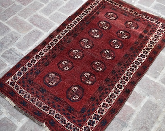 Könnte beinhalten: Ein roter Teppich mit traditionellem persischem Design. Der Teppich hat einen dunkelblauen Rand mit einem weißen und cremefarbenen Muster. Die Mitte des Teppichs zeigt ein sich wiederholendes Muster aus stilisierten Blumen.