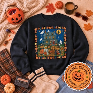 May include: A black crewneck sweatshirt featuring a central graphic of a haunted house with ghosts, a witch on a broom, and five teddy bears in Halloween costumes. The design is framed by a border of pumpkins, moons, and stars in orange and yellow.