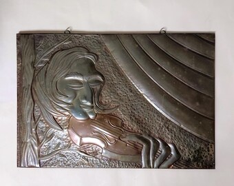 May include: A metal wall art piece depicting a person playing a violin. The artwork features a detailed relief of a person's face, hair, and hands, with the violin in the center. The color palette includes silver, copper, and bronze tones.