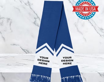 May include: A royal blue scarf with white chevron design and fringe. The scarf has the text "YOUR DESIGN HERE" printed on a white section. A "MADE IN USA" emblem is in the upper right corner.