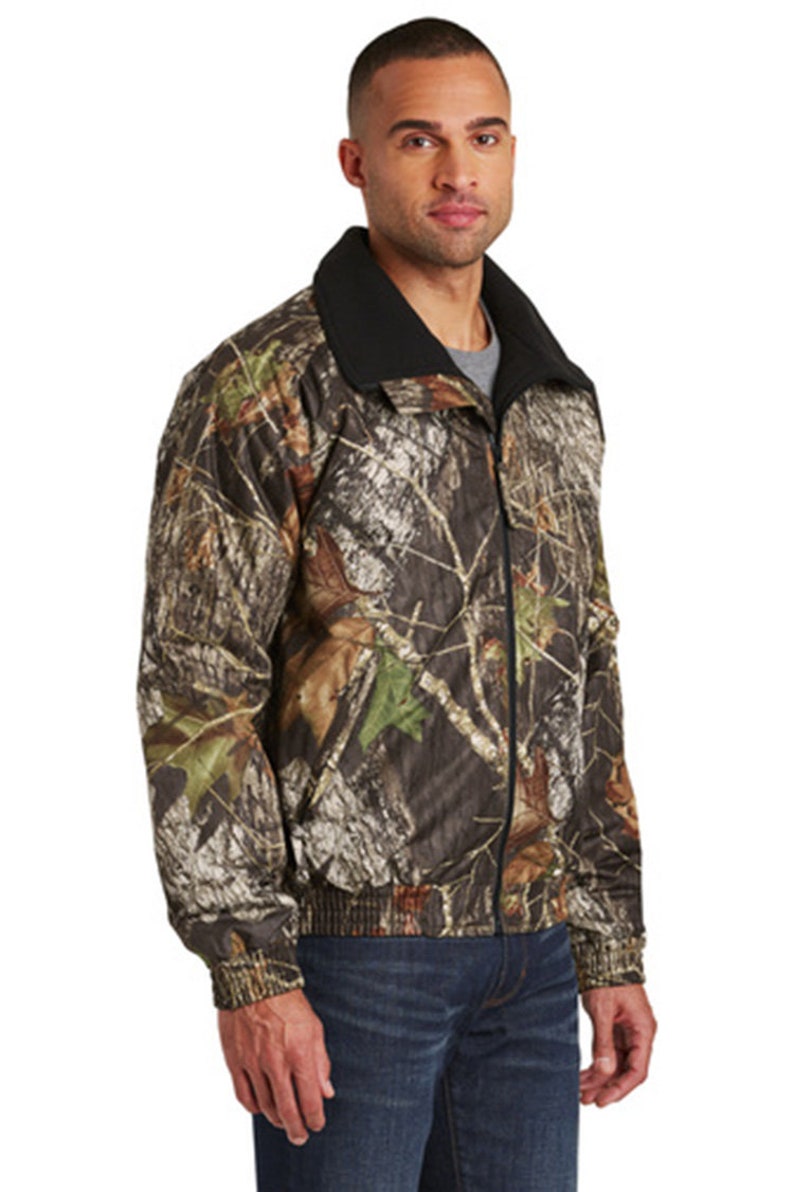 May include: A camouflage print jacket with a black fleece lining. The jacket has a zipper closure and a stand-up collar.