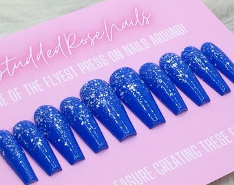Puede incluir: Un conjunto de diez uñas postizas largas en forma de ataúd, de color azul vibrante, salpicadas de purpurina blanca. Las uñas están dispuestas sobre una tarjeta rosa con el texto "Studded Rose Nails" y "ME OF THE FLYEST PRESS ON NAILS AROUND!"