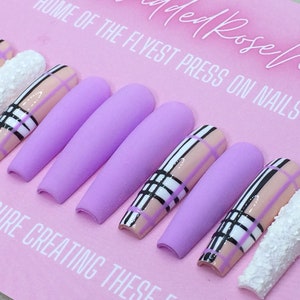 May include: Set of lavender press-on nails with a plaid design in black, white, and pink. The text "ed Rose nails" and "HOME OF THE FLYEST PRESS ON NAILS AROUND!" is visible on the pink background.