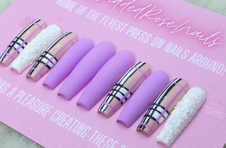 May include: Set of lavender press-on nails with a plaid design in black, white, and pink. The text "ed Rose nails" and "HOME OF THE FLYEST PRESS ON NAILS AROUND!" is visible on the pink background.