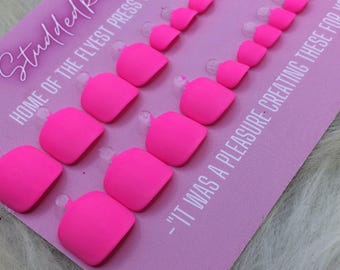 May include: A set of neon pink press-on nails arranged in two rows on a light purple display card. The card features the text StuddedRoseNails, HOME OF THE FLYEST PRESS ON NAILS AROUND!, and -IT WAS A PLEASURE CREATING THESE FOR YOU.