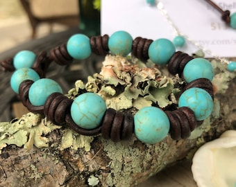 May include: A brown leather bracelet with turquoise beads. The bracelet is on a wooden surface.