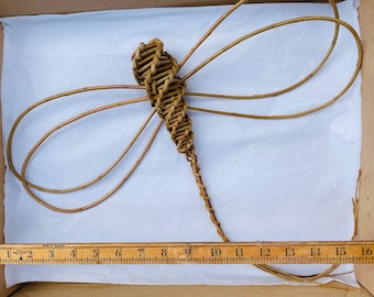 May include: A woven willow dragonfly sculpture with a brown and tan colour. The dragonfly is approximately 40 cm long.