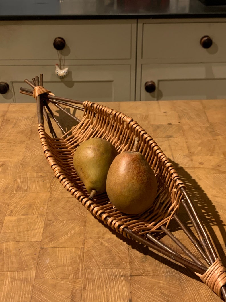 Pode incluir: Duas peras verdes em uma cesta de vime tecida com uma al&ccedil;a marrom. A cesta est&aacute; sobre uma superf&iacute;cie de madeira.