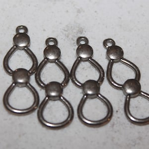 Könnte beinhalten: Fünf silberne Anhänger aus Metall in Tropfenform mit einer Öse oben. Jeder Anhänger besteht aus drei miteinander verbundenen Tropfenformen.