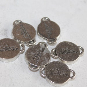 May include: Five silver-toned metal charms with the words "Classic Hardware" engraved on each. The charms have a loop on each side.