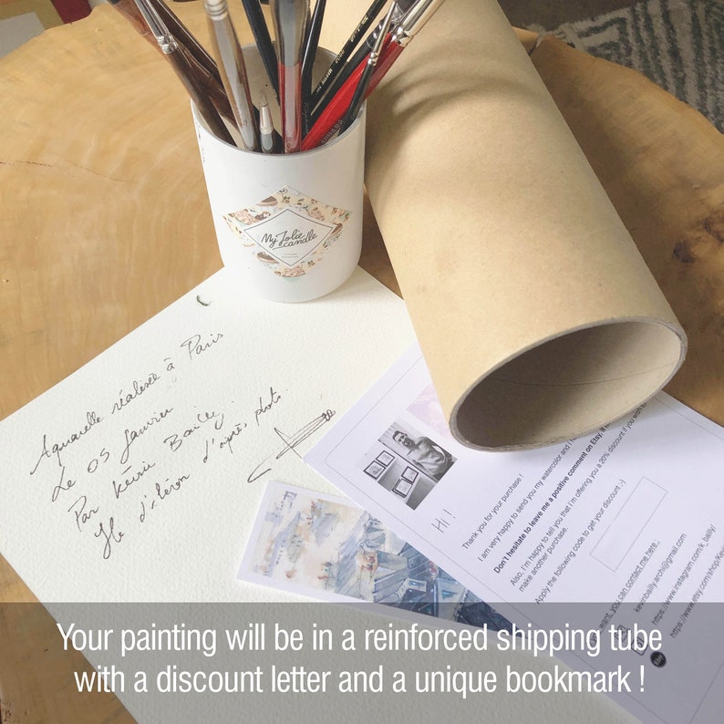 Puede incluir: Una acuarela que representa una escena callejera parisina con una nota manuscrita en franc&eacute;s que dice "Aquarelle r&eacute;alis&eacute;e &agrave; Paris le 05 Janvier Par Kevin Bailly, d'apr&egrave;s photos." La pintura se empaqueta en un tubo de env&iacute;o reforzado con una carta de descuento y un marcap&aacute;ginas &uacute;nico.