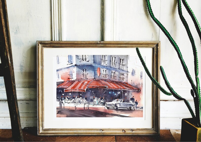 Puede incluir: Una pintura de acuarela en un marco dorado representa una escena de calle parisina con un caf&eacute; bajo un toldo a rayas rojas y blancas. La gente est&aacute; sentada en mesas fuera del caf&eacute;, y un coche est&aacute; aparcado en la calle. La pintura est&aacute; sobre un fondo blanco.