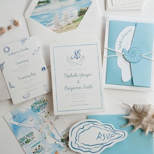 May include: A wedding stationery suite featuring a white envelope with a coastal watercolour liner, a blue and white invitation for Nephele Yeager and Benjamin Scott, a map card, an RSVP card shaped like an oyster shell, and a light blue folder.