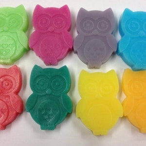 May include: Eight colourful owl-shaped soaps. The soaps are in shades of green, pink, purple, blue, red, teal, yellow, and orange. Each soap has a heart design on the front.