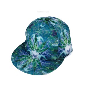 Könnte beinhalten: Eine Baseballkappe mit gebogenem Schirm in grün und blau. Das Muster zeigt ein stilisiertes Blattdesign.