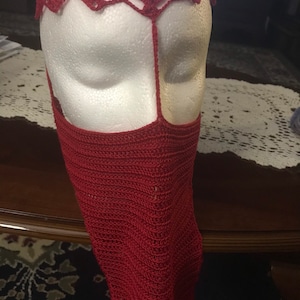 May include: A red crocheted face mask with a matching headband. The mask covers the nose and mouth and has a decorative design.