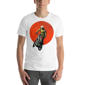 May include: White t-shirt with a graphic of a person riding a motorcycle in front of a red sun.