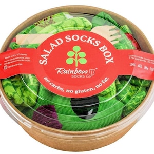 Puede incluir: Un contenedor rojo y blanco con una tapa transparente lleno de calcetines verdes y rojos. El contenedor tiene el texto "Salad Socks Box" y "Rainbow Socks". El texto también dice "no carbs, no gluten, no fat".