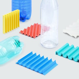 Pu&ograve; includere: Una collezione di sottobicchieri in plastica ondulata e testurizzata di diversi colori: blu, rosso, verde e giallo. I sottobicchieri sono disposti su una superficie bianca con due bottiglie di plastica trasparenti.