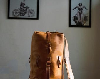 Könnte beinhalten: Eine große braune Ledertasche mit mehreren Riemen und Schnallen. Die Tasche hat eine zylindrische Form und ist aus dickem, strapazierfähigem Leder gefertigt.