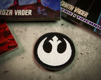 Écusson thermocollant REBEL ALLIANCE représentant une galaxie lointaine. Écusson brodé en noir et blanc. Décoration pour vêtements et costume de cosplay.