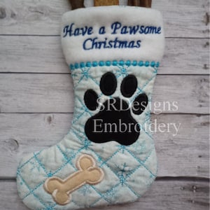 Peut inclure: Une chaussette de Noël bleue et blanche avec un motif de patte et d'os. La chaussette est brodée avec le texte "Have a Pawsome Christmas".