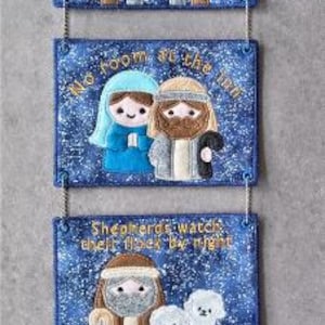 May include: A blue fabric Christmas wall hanging with four rectangular panels. The top panel reads "Holy Night" and depicts a manger scene. The other panels show Mary and Joseph, shepherds, and the Three Wise Men. Each panel has a decorative border.
