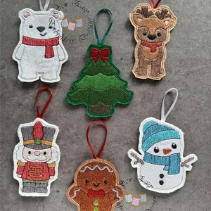 May include: A collection of six Christmas ornaments. The ornaments include a polar bear with a red scarf, a green Christmas tree with a red bow, a reindeer with a red scarf, a nutcracker, a gingerbread man with a red bow tie, and a snowman with a blue hat and scarf.