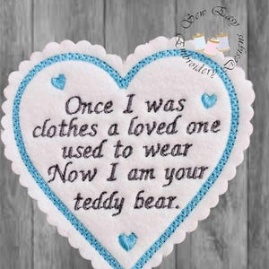 May include: A heart-shaped embroidered patch with a white center and a blue scalloped border. The text "Once I was clothes a loved one used to wear Now I am your teddy bear" is stitched in black. Small blue hearts are embroidered on the patch.