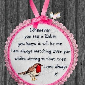 Pode incluir: Decoração bordada redonda com uma fita rosa. O texto diz: «Whenever you see a Robin...Love always». O design apresenta um pisco-de-peito-ruivo e uma borda rosa ondulada. Ideal para decoração de casa.