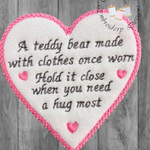 May include: A heart-shaped embroidered patch with a white center and pink trim. The patch features the text "A teddy bear made with clothes once worn. Hold it close when you need a hug most."