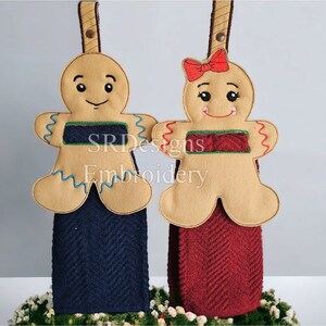 Portasciugamani a forma di omino e bambina di pan di zenzero, dimensioni approssimative 199 mm x 263 mm. Sono necessari i telai da 8" x 12" e 5" x 7" con disegno da ricamo.