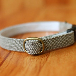 May include: A beige and white woven cat collar with a brass buckle.
