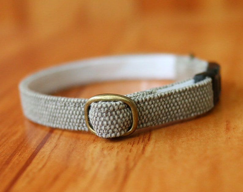 May include: A beige and white woven cat collar with a brass buckle.