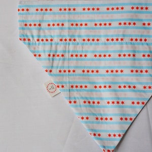 May include: A white bandana with blue and red stripes and red stars. The bandana has a small white tag with the text "The Original" on it.