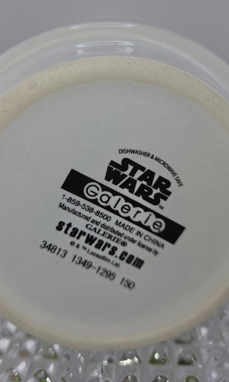 Może przedstawiać: Biały ceramiczny przedmiot z logo Star Wars i słowem "Galerie" w kolorze czarnym. Widoczny jest r&oacute;wnież tekst "Dishwasher & Microwave Safe". Wyprodukowano w Chinach.