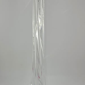 May include: Clear glass vase with a twisted, elongated design. The vase has a flared base and a tall, slender neck. The glass has a rippled texture, and the vase is suitable for displaying flowers or as a decorative piece.