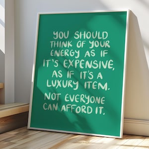 May include: A framed art print with a teal background and white text that reads: "YOU SHOULD THINK OF YOUR ENERGY AS IF IT'S EXPENSIVE, AS IF IT'S A LUXURY ITEM. NOT EVERYONE CAN AFFORD IT."