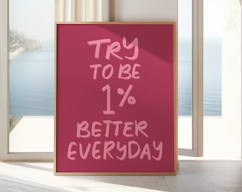 Può includere: Un poster incorniciato con la scritta "Try to be 1% better everyday" in lettere rosa su sfondo rosa intenso. Il poster ha una cornice in legno marrone chiaro ed è esposto in una stanza luminosa con vista sull'oceano.